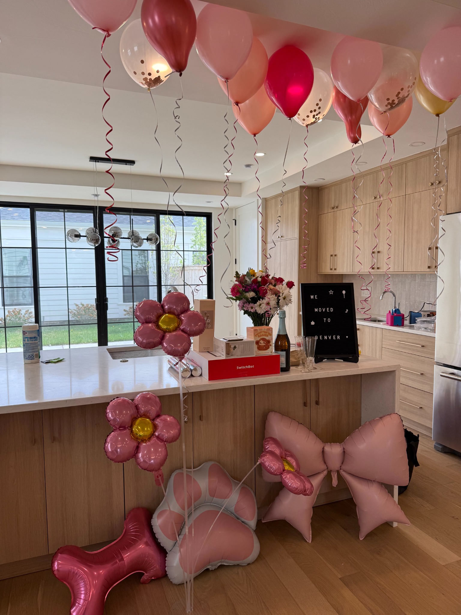 Kitchen decorated with pink balloons, flowers, and new-home gifts